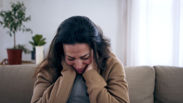 Front view of crying sad and depressed woman indoors, mental health concept.