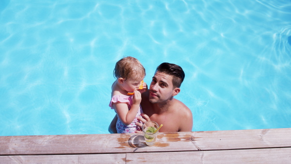 Young father with small daughter in swimming pool outdoors in backyard garden, playing.