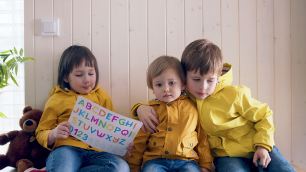 Small children sitting in hall in the morning at home, getting ready for school.