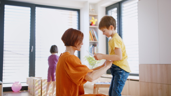 Mother with small children in bedroom in the morning at home, everyday life concept.