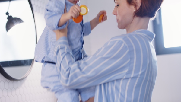 Mother with small toddler daughter in pajamas in bathroom at home, talking.