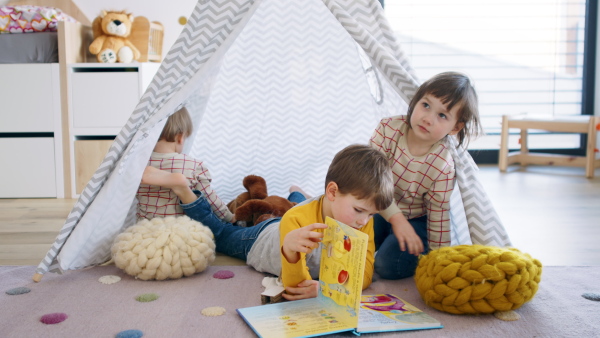 Small children in bedroom indoors at home, playing in tent.