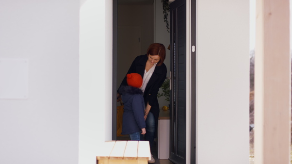 Mother with two small children in the morning, leaving home for work and school.