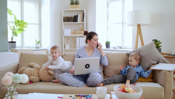 Mother and small with pajamas, laptop and smartphone children working in home office, quarantine concept.