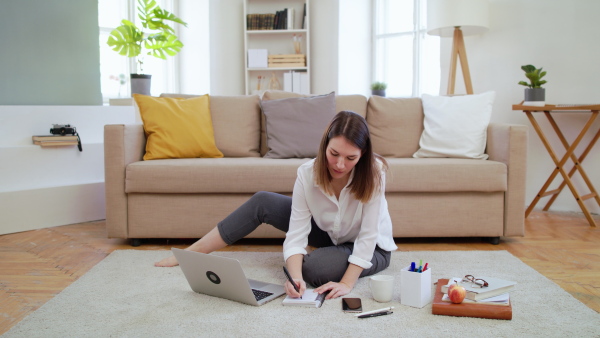 Businesswoman with laptop sitting and working on floor in home office, quarantine concept.