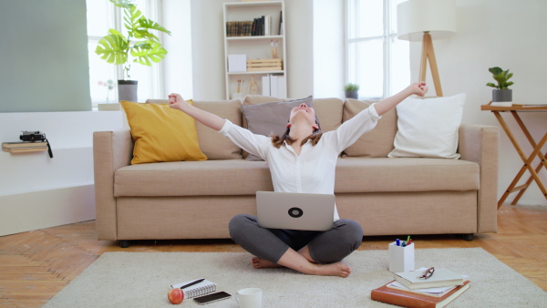 Businesswoman with laptop working in home office in quarantine, expressing excitement.