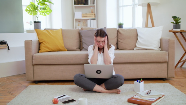 Front view of businesswoman with laptop working in home office, hearing bad news.