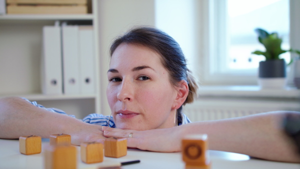 Close-up of young woman with board game looking at camera indoors at home, quarantine concept.