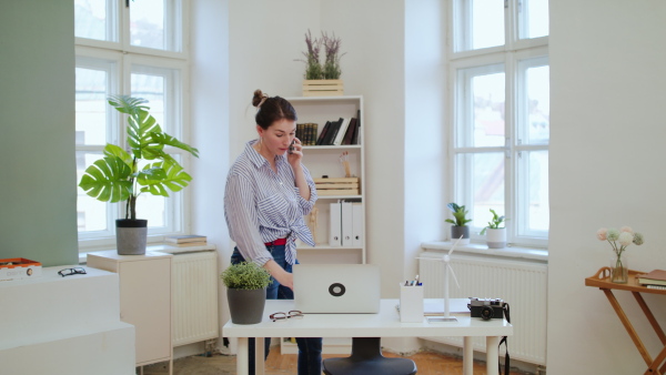 Young businesswoman with laptop and smartphone working in home office, quarantine and lockdown concept.