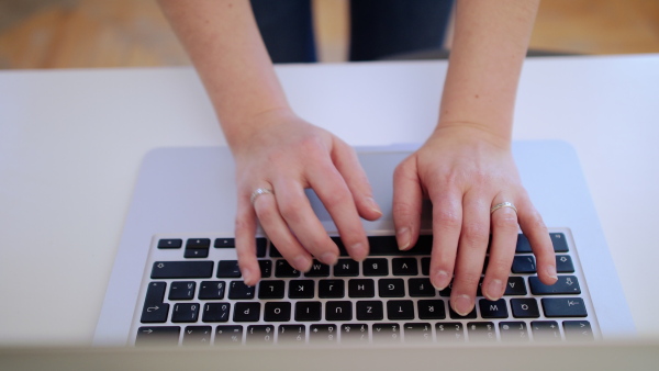 Hands of unrecognizable businesswoman with laptop working in home office, quarantine concept.