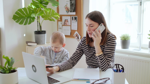 Mother with small child and laptop working in home office, quarantine concept.