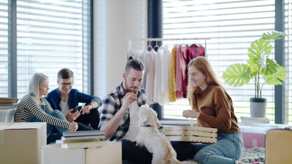 Group of cheerful young people with dog moving in new home, house sharing concept.