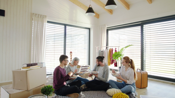 Group of young people with pet dog moving in new home, eating. House sharing concept.