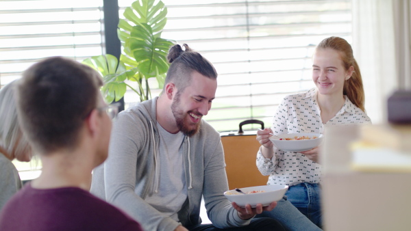 Group of young people moving in new home, eating. House sharing concept.