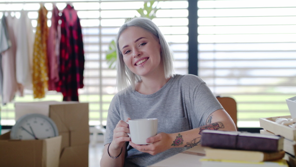 Portrait of young woman with coffee moving in new home, looking at camera.