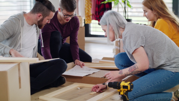 Group of young people assembling furniture in new home, house sharing concept.