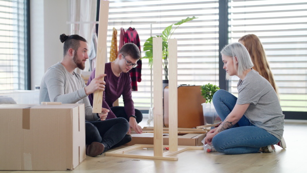 Group of young people assembling furniture in new home, house sharing concept.