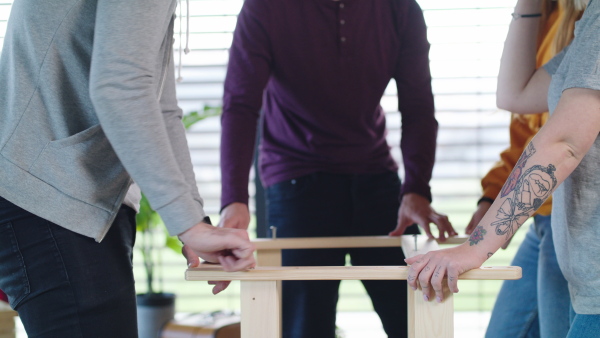 Midsection of unrecognizable young people assembling furniture in new home, house sharing concept.