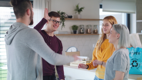 Group of cheerful young people high-fiving when moving in new home, house sharing concept.