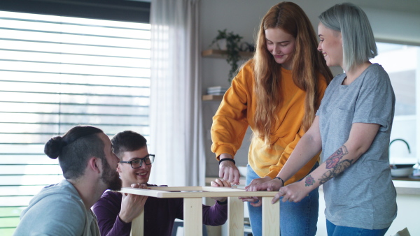 Group of young people assembling furniture in new home, house sharing concept.