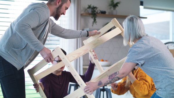 Group of young people assembling furniture in new home, house sharing concept.