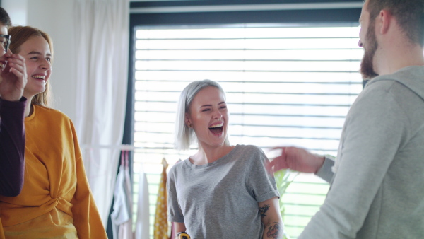 Group of young people laughing when assembling furniture in new home, house sharing concept.