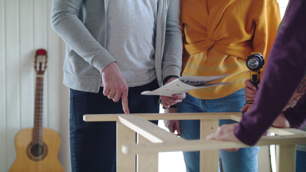 Group of young people assembling furniture in new home, house sharing concept.