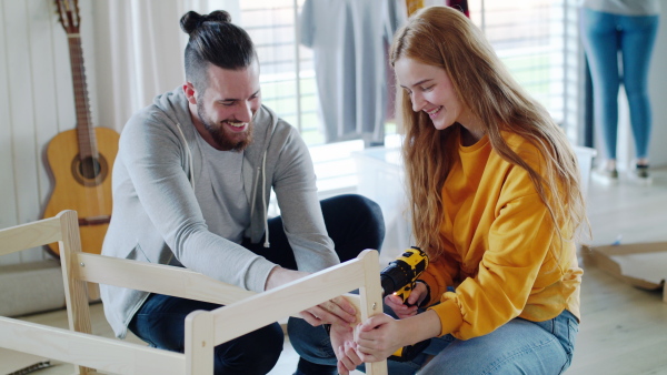 Group of young people assembling furniture in new home, house sharing concept.