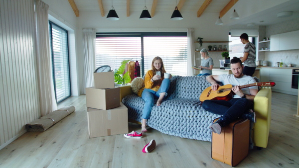 Group of cheerful young people with guitar and dog moving in new home, house sharing concept.