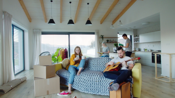 Group of cheerful young people with guitar and dog moving in new home, house sharing concept.