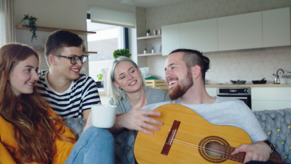 Group of cheerful young people relaxing in new home, house sharing concept.