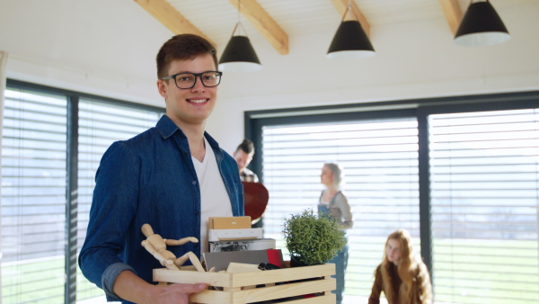 Portrait of young guy with friends moving in new home, house sharing concept.