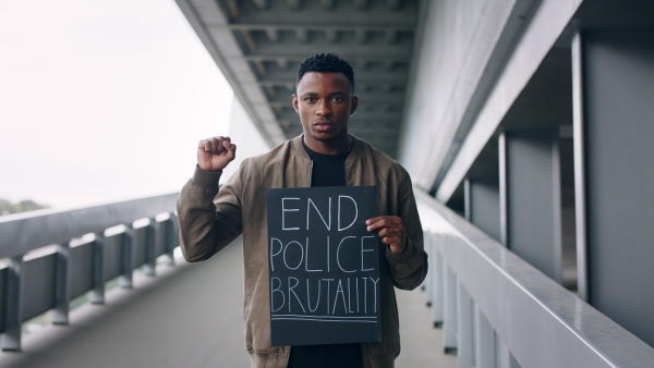 Young man with silence is violence sign standing outdoors in city, black lives matter concept.