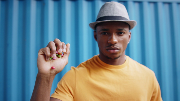 Portrait of man with skittles standing against blue background, black lives matter concept.