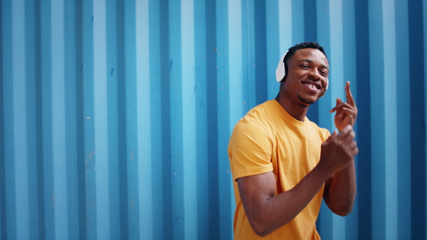 Young black man with sunglasses and headphones standing against blue background, black lives matter concept.