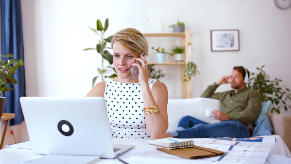 Portrait of young businesswoman with telephone indoors in home office, working.