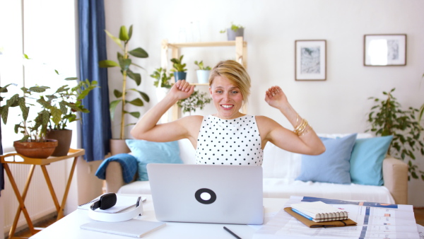 Cheerful young businesswoman with laptop indoors in home office, expressing excitement when working.