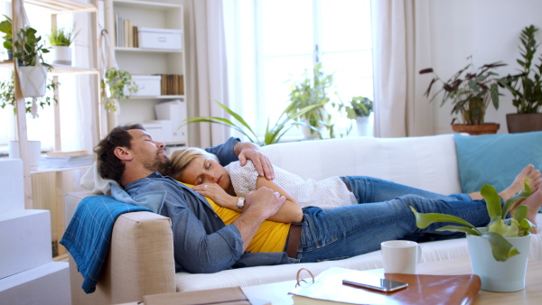 Happy mature couple in love lying on sofa indoors at home, sleeping.