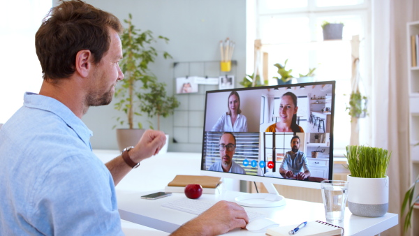 Mature businessman with laptop working indoors in home office, business call concept.