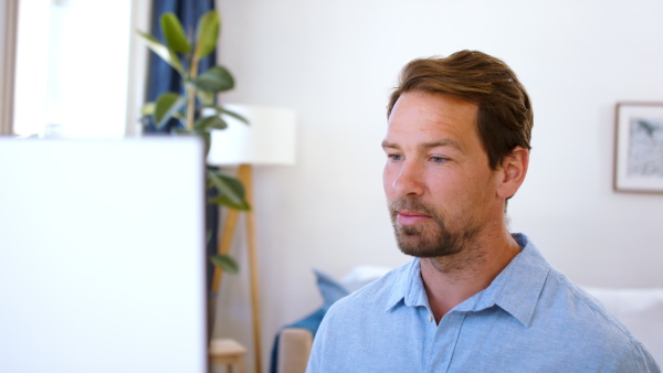 Mature businessman with computer working indoors in home office, business call concept.