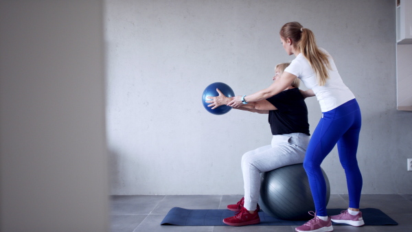 Portrait of senior woman exercising with personal trainer.