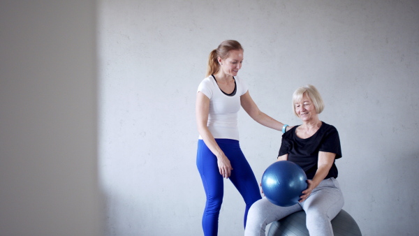 Portrait of senior woman exercising with personal trainer.