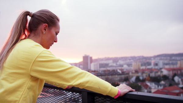 Young woman in yellow tracksuit doing stretching after run.