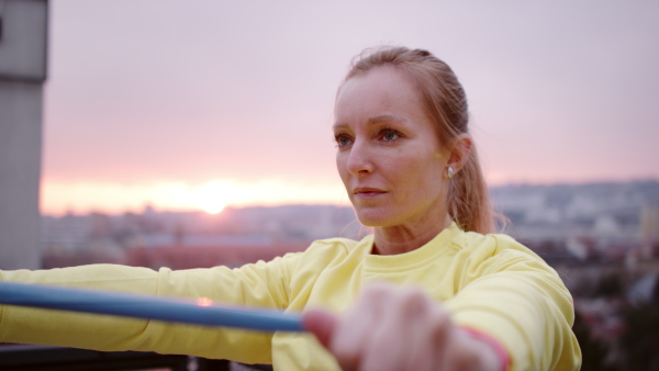 Young woman in yellow tracksuit doing stretching after run.