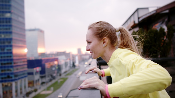 Young woman in yellow tracksuit doing stretching after run.