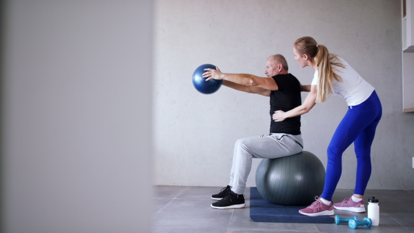 Portrait of senior man exercising with personal trainer.