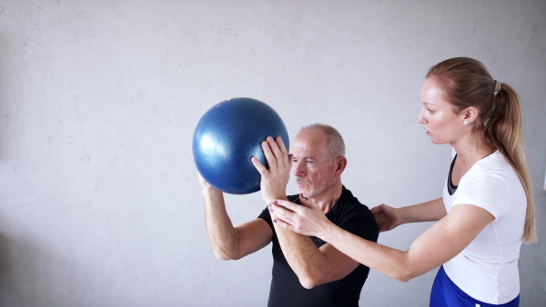 Portrait of senior man exercising with personal trainer.