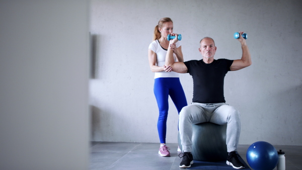 Portrait of senior man exercising with personal trainer.