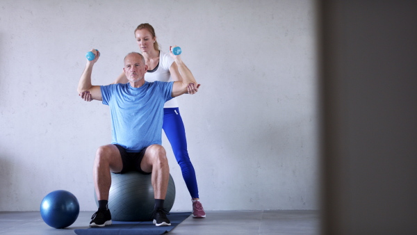 Portrait of senior man exercising with personal trainer.