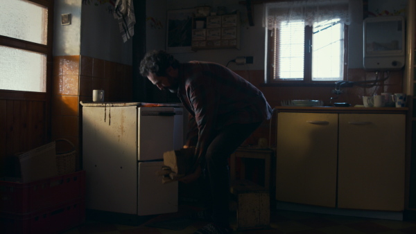 A side view of poor mature man sustaining fire in oven, poverty concept.